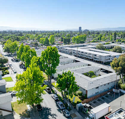 A view of a residential area with houses, trees, and a parking lot.