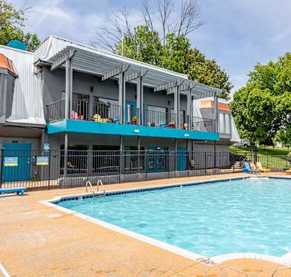 A swimming pool in front of a building with a blue fence around it.
