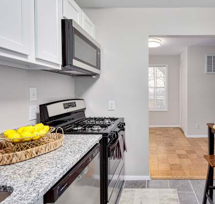 A kitchen with a black stove top oven and a black microwave above it.