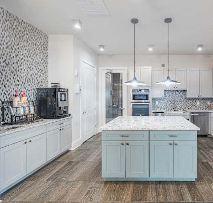 a large white kitchen with stainless steel appliances and a marble counter top