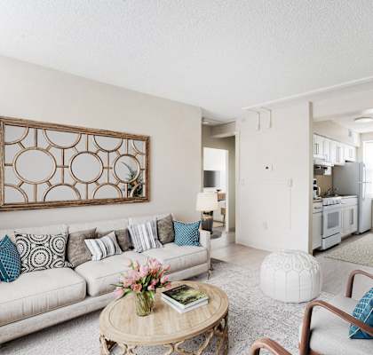 A living room with a couch, a chair, a coffee table, and a potted plant.