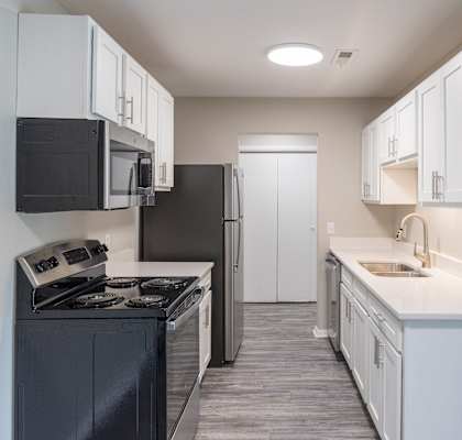 an empty kitchen with white cabinets and a black stove and refrigerator