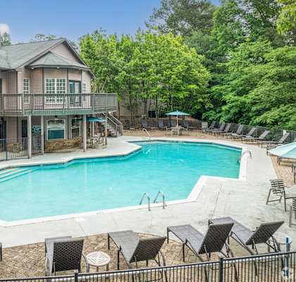 a pool with chairs and a house with a resort style pool