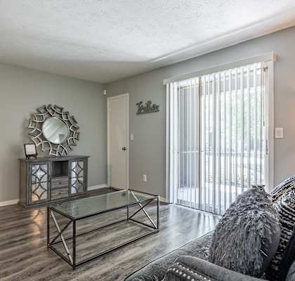 A living room with a glass coffee table and a grey couch.