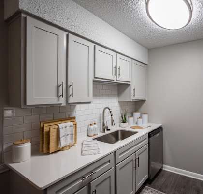 A kitchen with a black refrigerator and white cabinets.