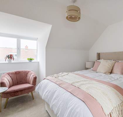 A bedroom with a bed, chair, and lamp.