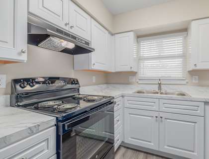 A kitchen with white cabinets and a black stove top.