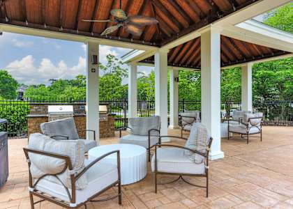 A patio with a white couch and chairs under a roof.