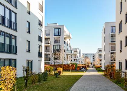 A long walkway separates two rows of white apartment buildings.