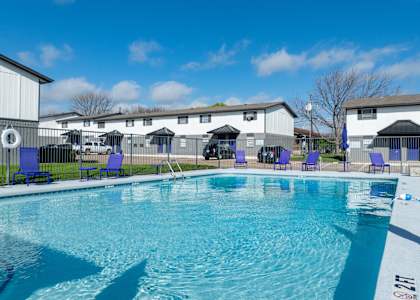A swimming pool with blue chairs and a white building in the background.