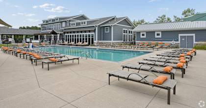 A large swimming pool with sun loungers and a building in the background.