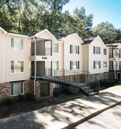 a row of white apartments with stairs and trees at Hidden Woods, Decatur, GA, 30035