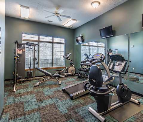 A gym with a variety of equipment including treadmills, weights, and exercise machines.