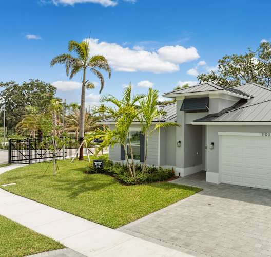 a house with a driveway and a garage with palm trees