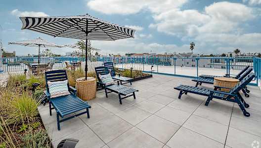 A patio with blue chairs and a striped umbrella.
