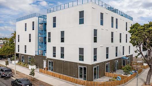 A white building with a blue balcony on the top floor.