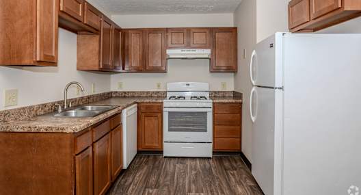 A kitchen with brown cabinets and white appliances.