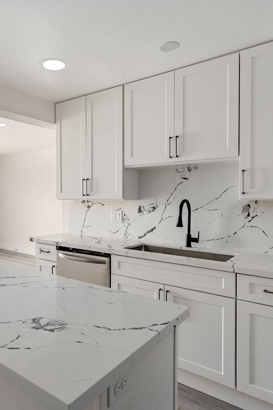 A modern kitchen with white cabinets and stainless steel appliances.