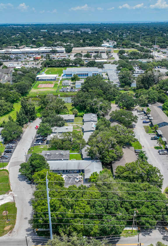 A bird's eye view of a green campus with buildings and cars.