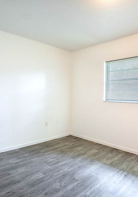 A room with a window and wooden flooring.