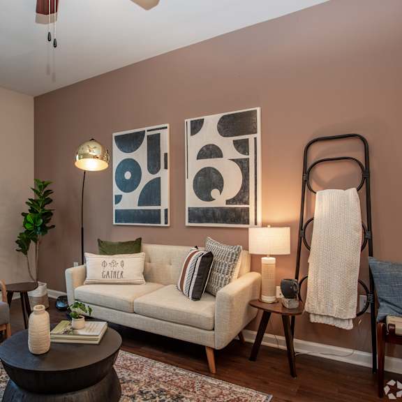 A living room with a white couch, a grey armchair, a coffee table, and a plant.