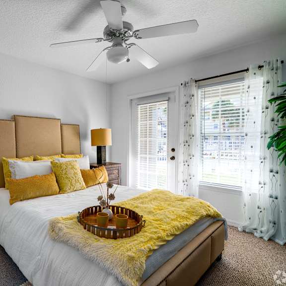 A bedroom with a white bed and yellow pillows.