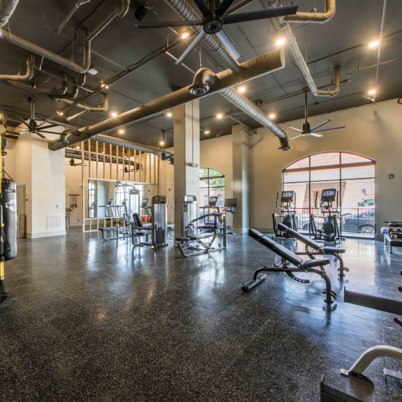 a gym with weights and cardio equipment on the floor and a glass door