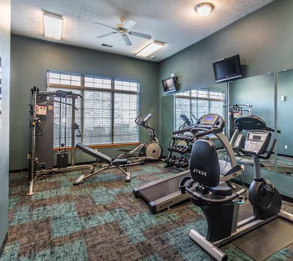 A gym with a variety of equipment including treadmills, weights, and exercise machines.