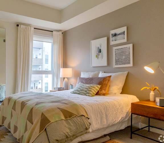 A bedroom with a large bed and a window with curtains.
