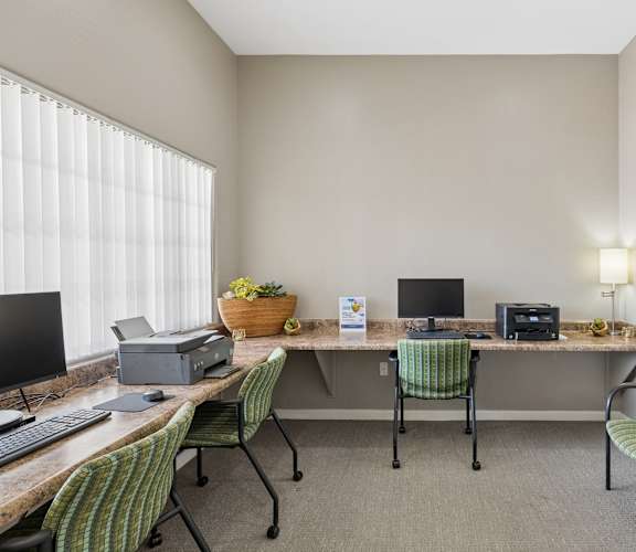 A room with a desk, chairs, and a printer.