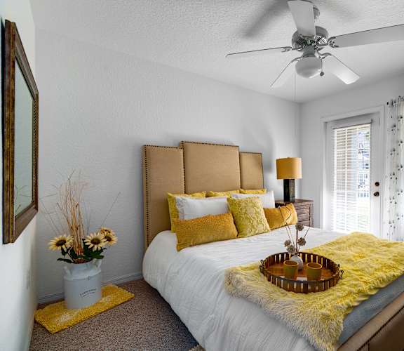 A bedroom with a white bed and yellow pillows.