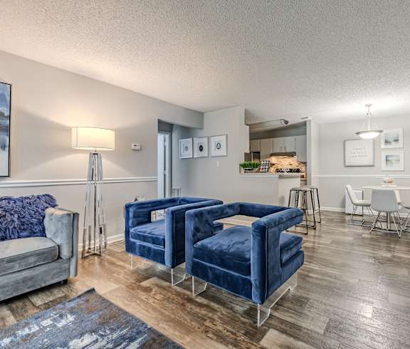 a living room with two blue couches and a kitchen with a table and chairs