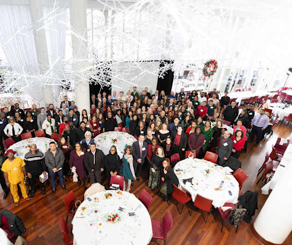 A group of people are gathered in a room for a holiday event.