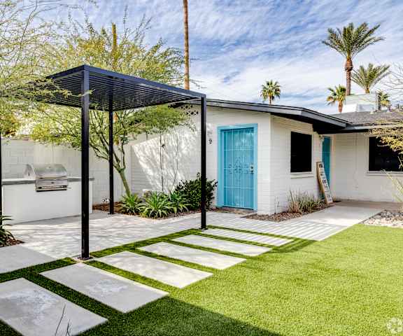 a small white house with a blue door and a yard with a stone walkway