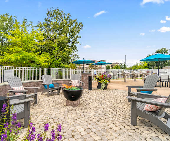 a patio with tables chairs and umbrellas and a fire pit at Sycamore at Tyvola, Charlotte, 28217