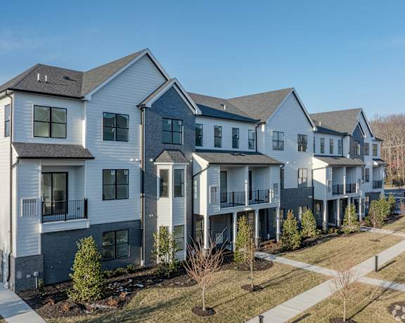 A row of modern houses with balconies and trees in front.