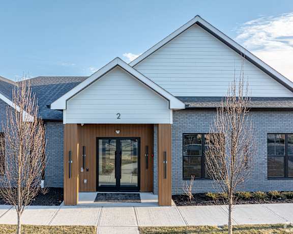 A modern building with a white front and a brown door.