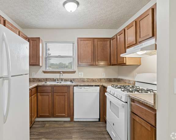 A kitchen with white appliances and wooden cabinets.
