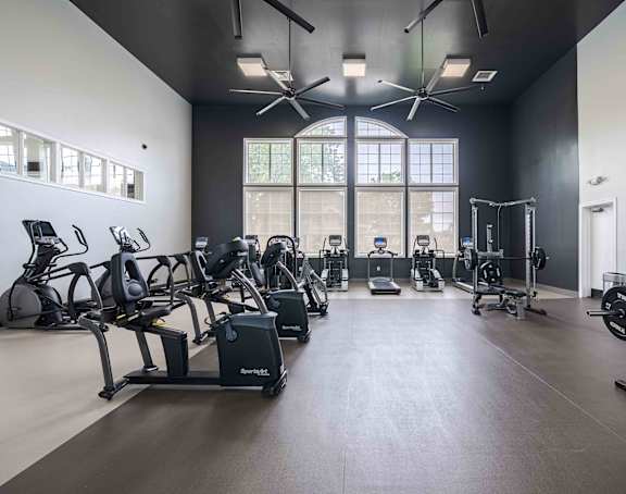 A gym with a variety of equipment including treadmills, stationary bikes, and weightlifting machines.