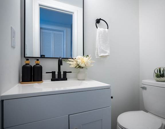 a white bathroom with a sink and toilet and a mirror