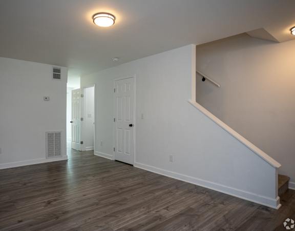an empty living room with white walls and wood flooring
