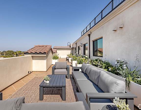 A patio with a table and chairs is surrounded by plants.