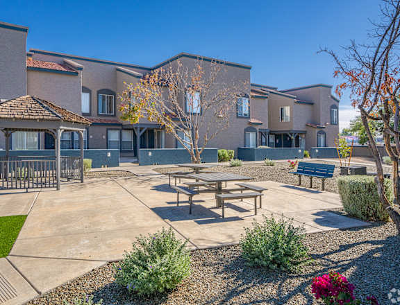 a picnic area with benches and a gazebo in front of a building