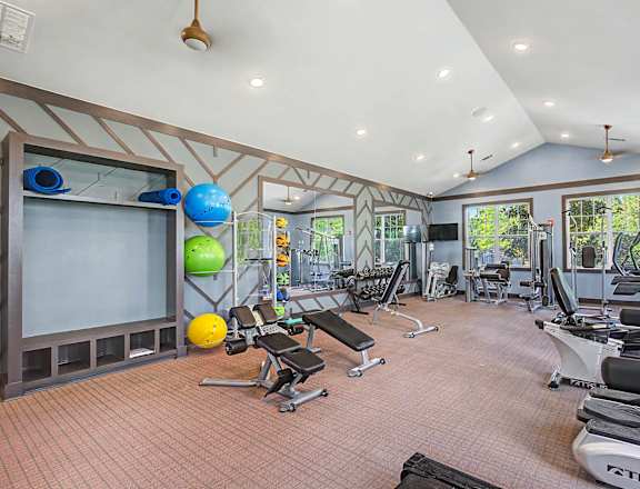 A spacious gym with a variety of equipment and a large mirror on the wall.