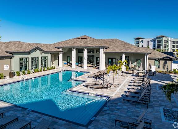 A large swimming pool in front of a building with a poolside lounge.