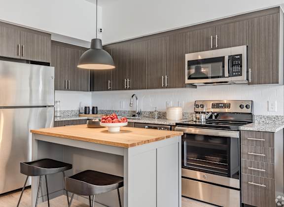 A modern kitchen with a wooden island and stainless steel appliances.