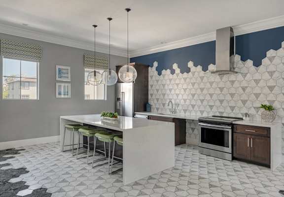 A kitchen with a white island and a black and white floor.
