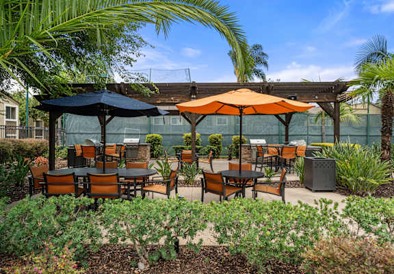 A patio with tables and chairs under umbrellas.