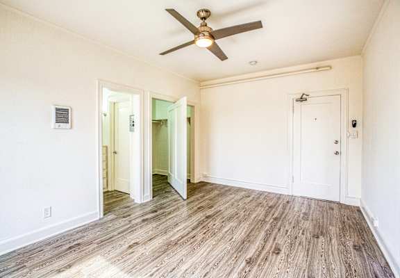 the living room of an empty house with a ceiling fan