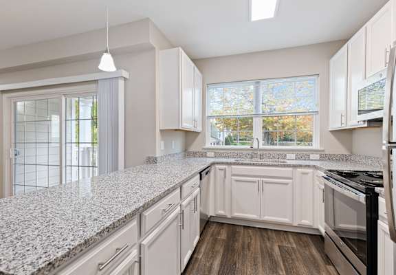 an empty kitchen with white cabinets and granite counter tops at The Enclave at Crossroads, North Carolina, 27606